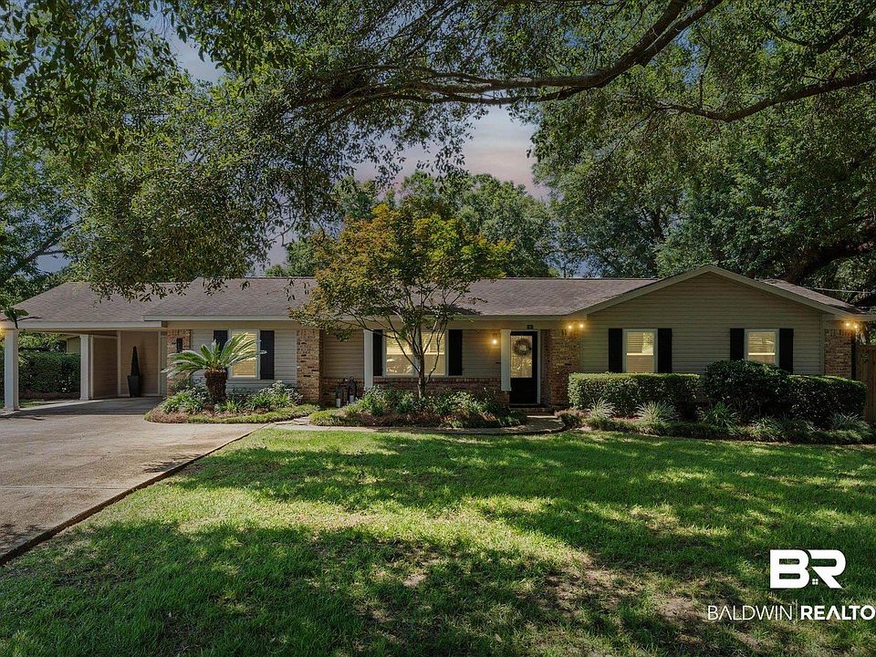 Ranch-style residence featuring a carport, brick and siding exterior, established front landscaping, and a privacy fence