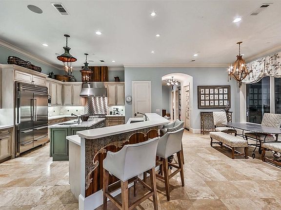 The spacious gourmet kitchen has high-end appliances, white quartzite kitchen counters, Carrera marble island with vegetable sink, breakfast bar with room for six or more, loads of cabinetry and counterspace.