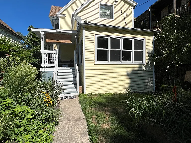 Back of house. The backyard has multiple garden beds and city compost bin.