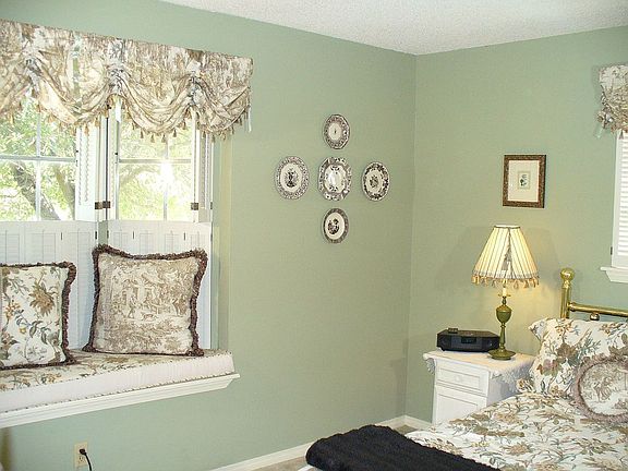 The first bedroom has bay windows and wood shutters.