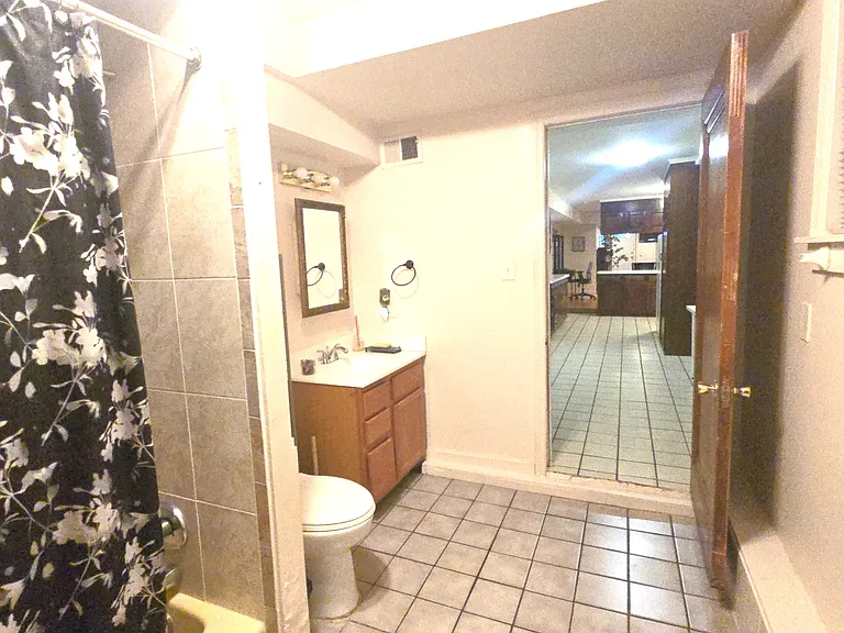 View of the bathroom as you leave the bedroom. Note distant view of front door.
