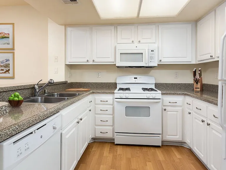 Classic Package I kitchen with white appliances, faux granite countertops, white shaker cabinetry, and hard surface flooring