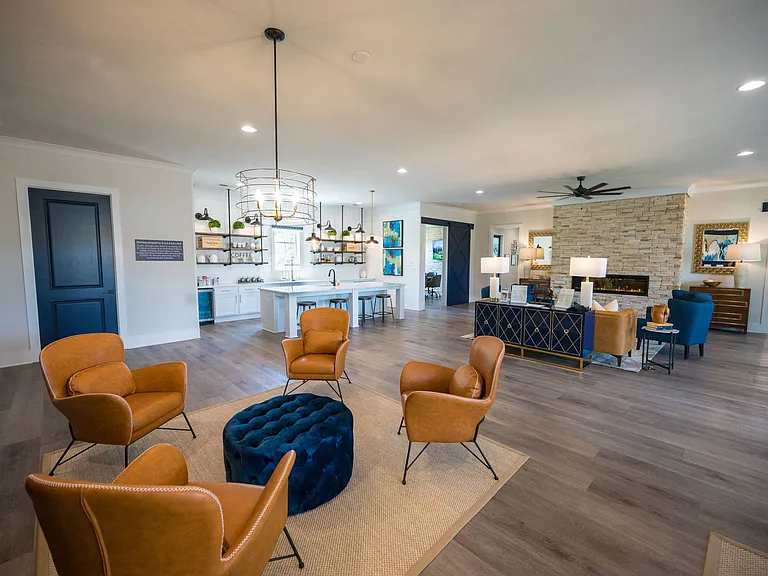 Kitchenette inside the Clubhouse with expansive island that offers bar seating and a microwave. Looking onto the living room area with ample seating, and fireplace.
