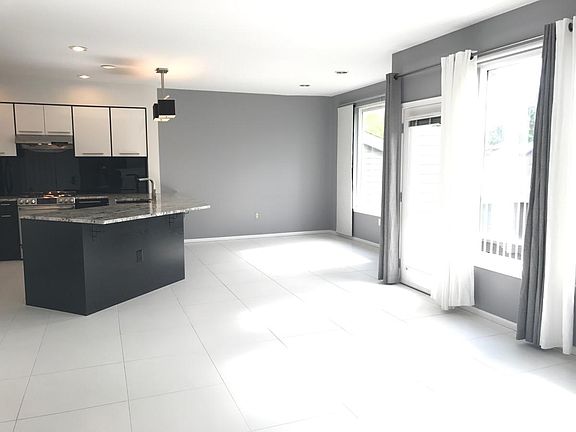 Spacious great room with clean white tiles, high ceilings, f
