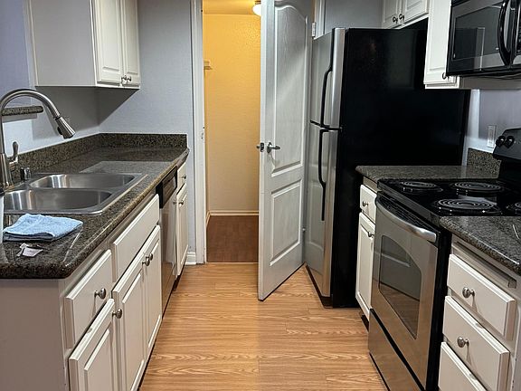 Kitchen refrigerator stove top/oven, microwave and dishwasher. Also includes garbage disposal. At the far end behind the door is the washer and dryer