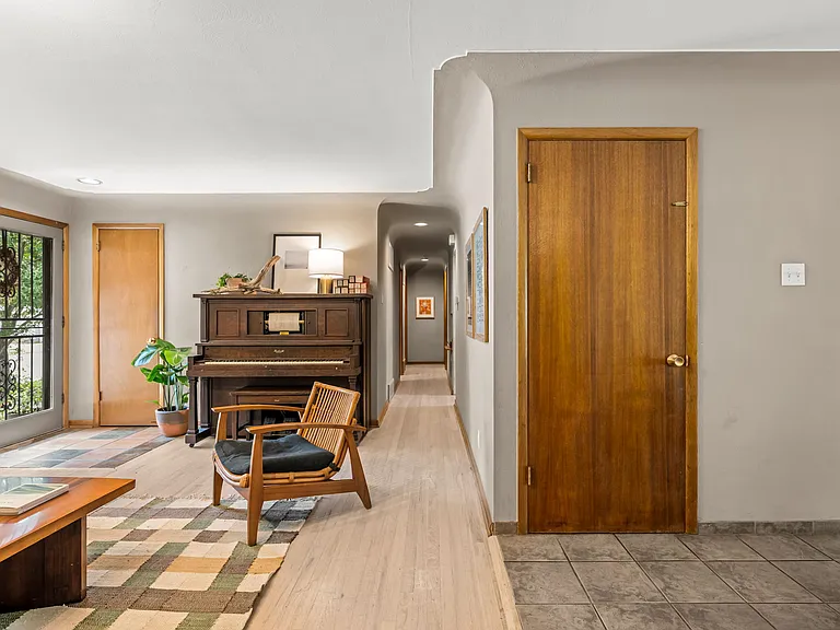 Hallway to primary suite and two bedrooms; door leads to basement apartment and storage