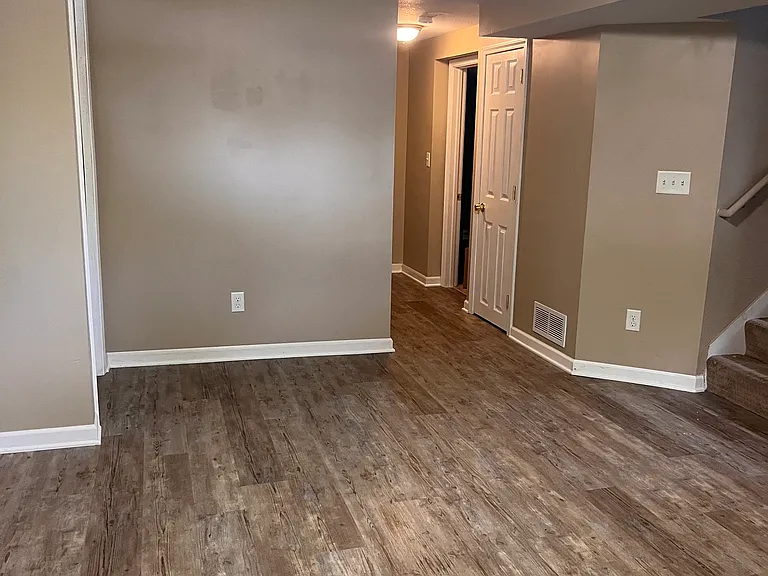 Lower-level family room facing the hallway of the lower bedroom and office. No furniture in this photo.