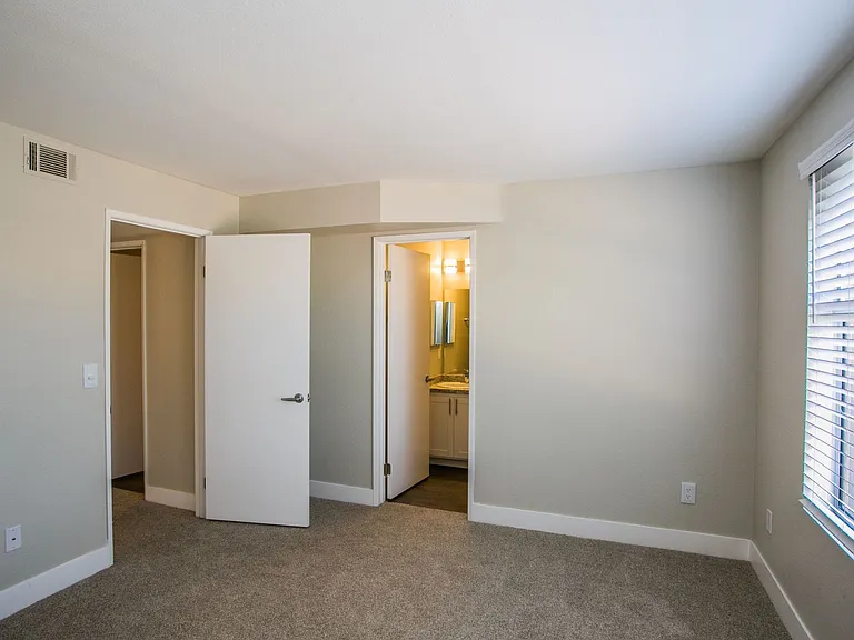 Bedroom with large baseboards, two-tone paint, and door to bathroom.