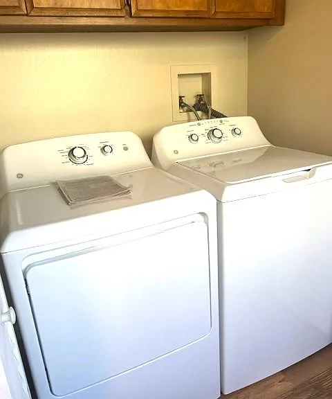 newer washer and dryer with above storage cabinets behind folding doors
