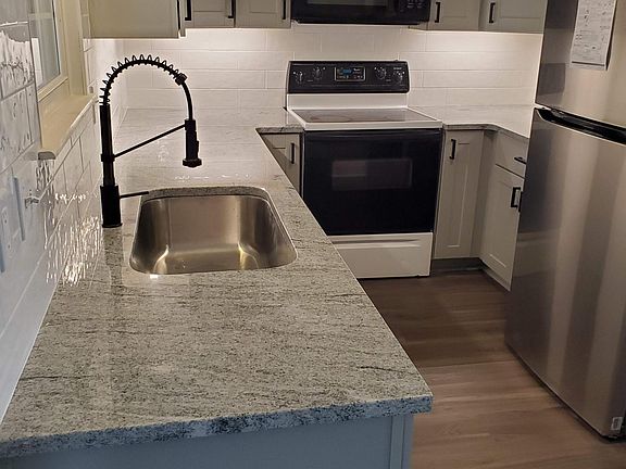 Sparkling New Kitchen with Granite Counters and tiled backsplash.