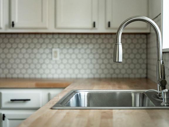 Updated kitchen with new butcher block countertops and backsplash.