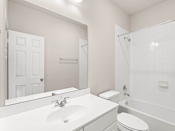The secondary bath features tile flooring, white cabinetry and light countertops and a shower tub co