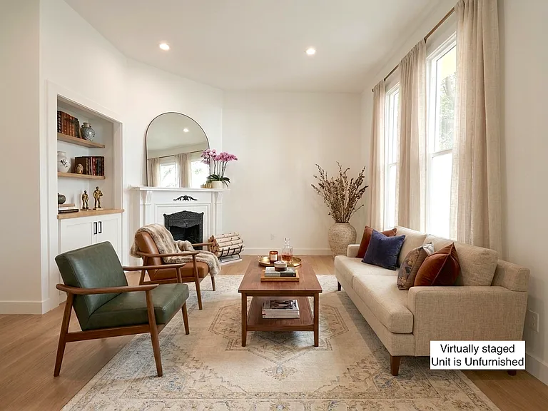 Living room with large windows, decorative fireplace and built in shelving (virtually staged)