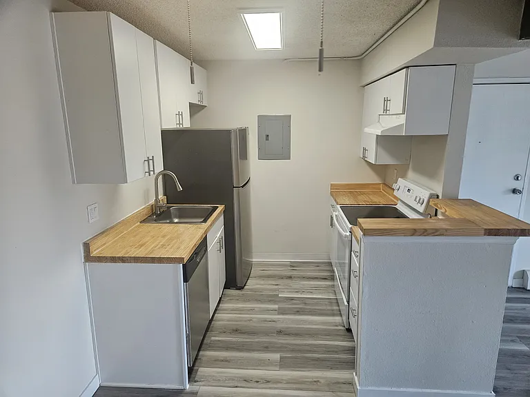 Kitchen with stainless steel fridge, butcher block countertops and updated cabinets.