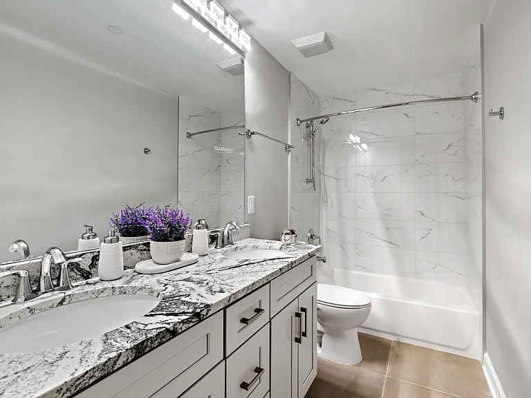 Stunning modern second bathroom featuring double-sink vanities and a soaking tub.