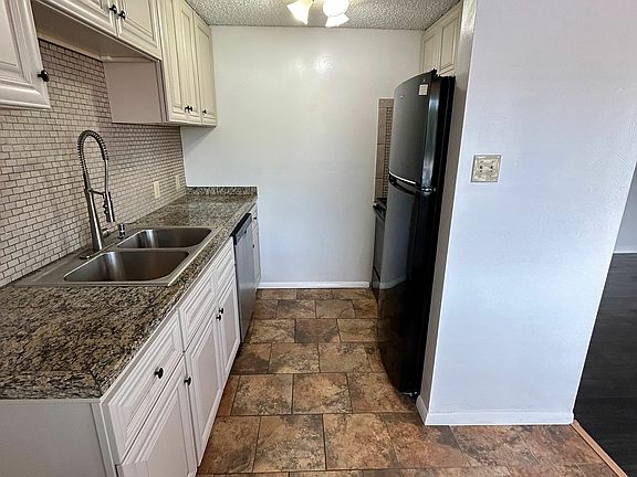 Charming kitchen with elegant granite countertops, stylish cabinetry, and a sleek stainless steel refrigerator.
