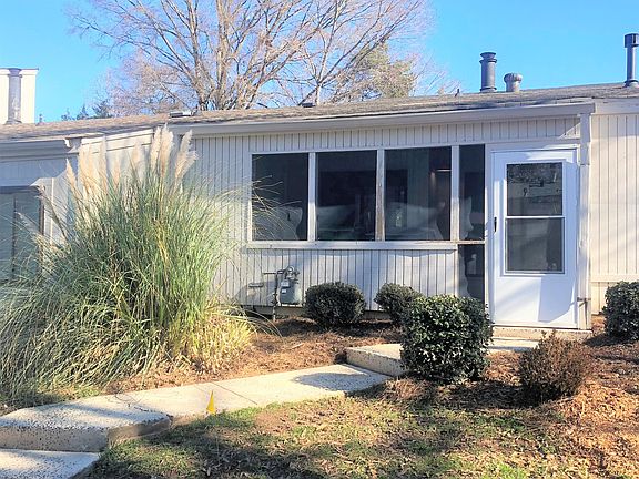Front view of townhome with landscaping and covered screened porch.
