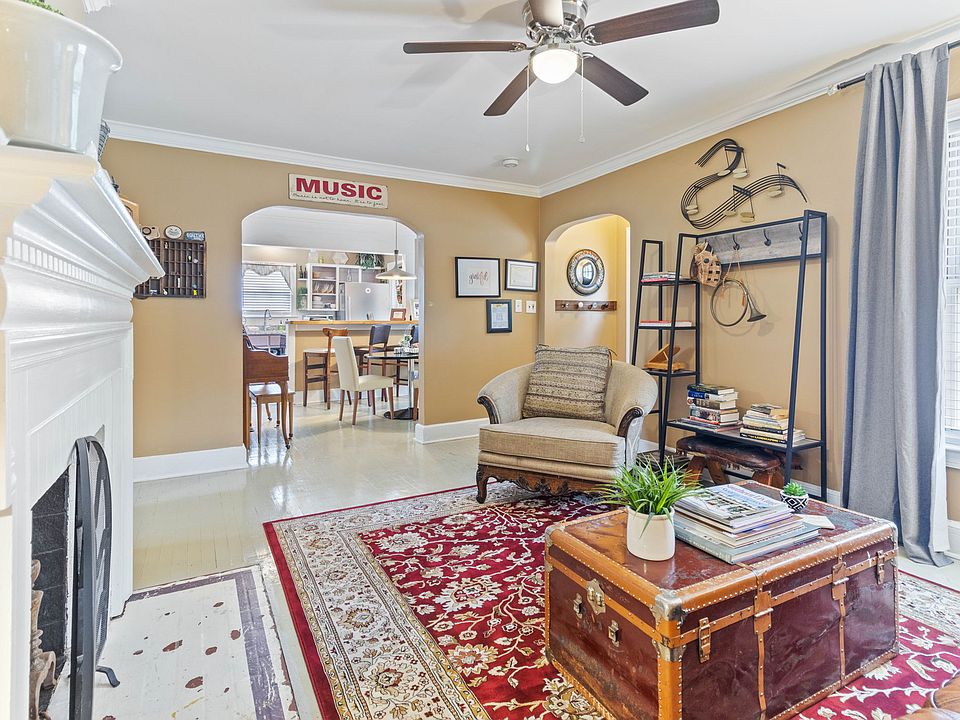 Cozy living room at Hunsucker's Place near Downtown Greensboro, featuring a comfortable leather couch, a functional writing desk, and an open-concept design connecting to the dining room with a piano and the fully equipped kitchen_perfect for relaxation