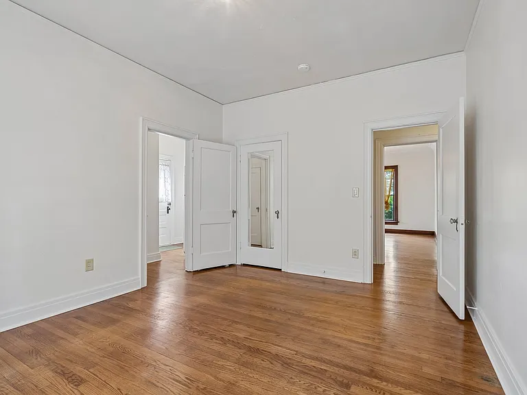 Bedroom 2. Door on left is transition space that has door to rear entrance and connects to kitchen. Door on right goes into hallway that connect to formal dining room straight and goes right to restroom and bedroom 1