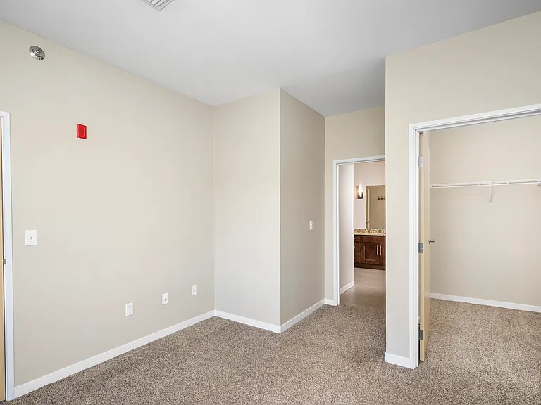 Bright and spacious bedroom with plush carpeting, featuring a large closet and en-suite bathroom, perfect for comfortable living. Bright and spacious bedroom with plush carpeting, featuring a large closet and en-suite bathroom, perfect for comfortable liv