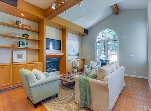 Living room with soaring vaulted ceilings, built-in shelving & cabinets, fireplace, bamboo/wood flooring