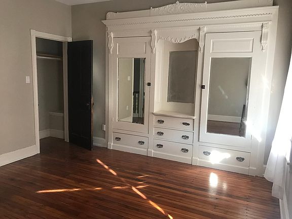 The front bedroom, facing south. Check out the great armoire and the closet on the left. Hardoowd floors and a ceiling fan. A nice large room that will help you face another pandemic Monday.