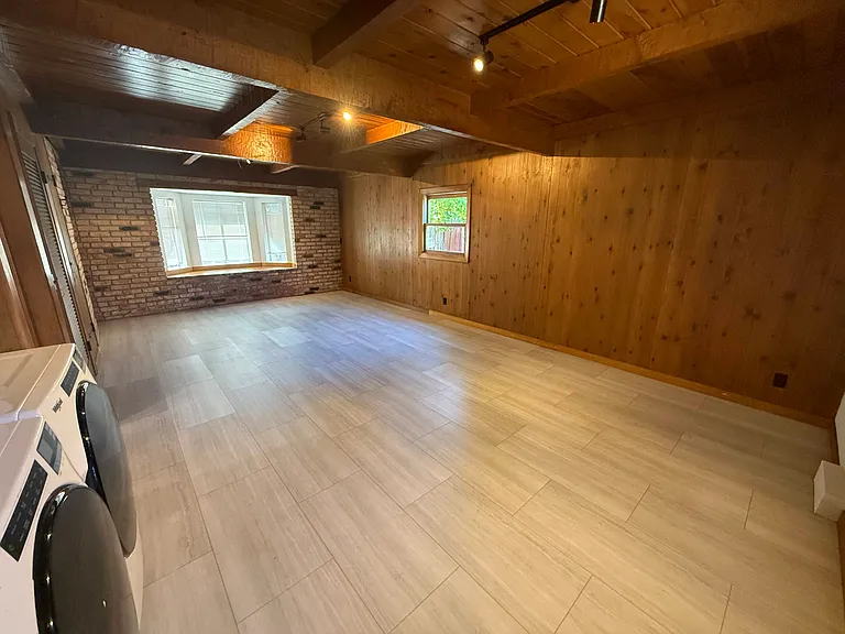 Spacious family room featuring wooden beam ceiling, a bay window, storage closets and a laundry closet with patio access to the backyard.