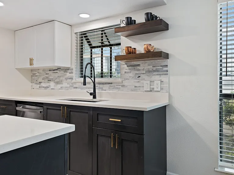 Kitchen featuring dishwasher, white cabinetry, sink, and tasteful backsplash