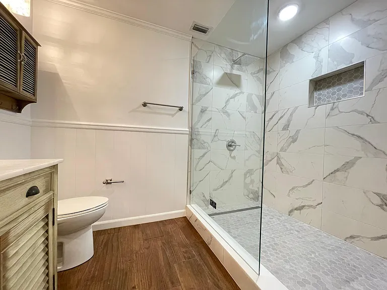 Rainfall Shower head, frameless glass wall, and a built in niche.