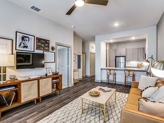 Gray finish package kitchen, living, and dining area with hard surface flooring and ceiling fan