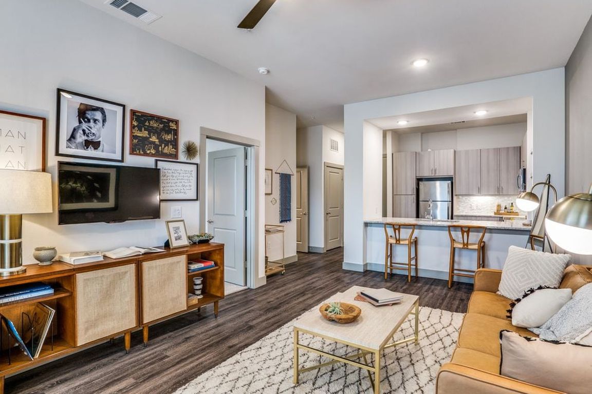 Gray finish package kitchen, living, and dining area with hard surface flooring and ceiling fan