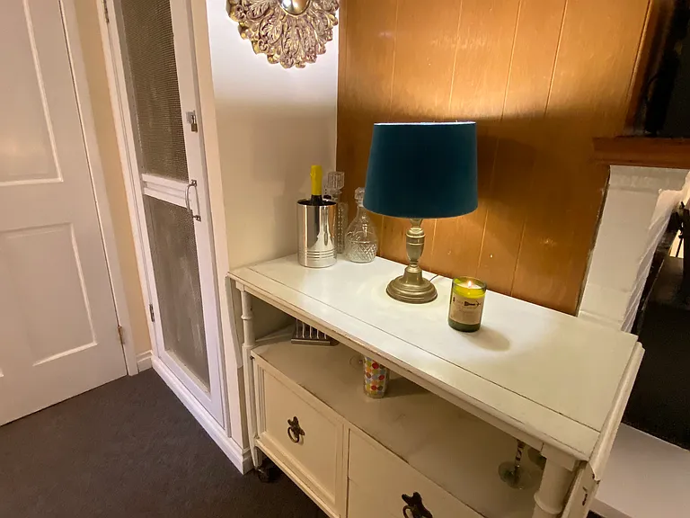 Bar cart with decanters, wine glasses, cocktail shaker, barware, wine cooler and wine rack.