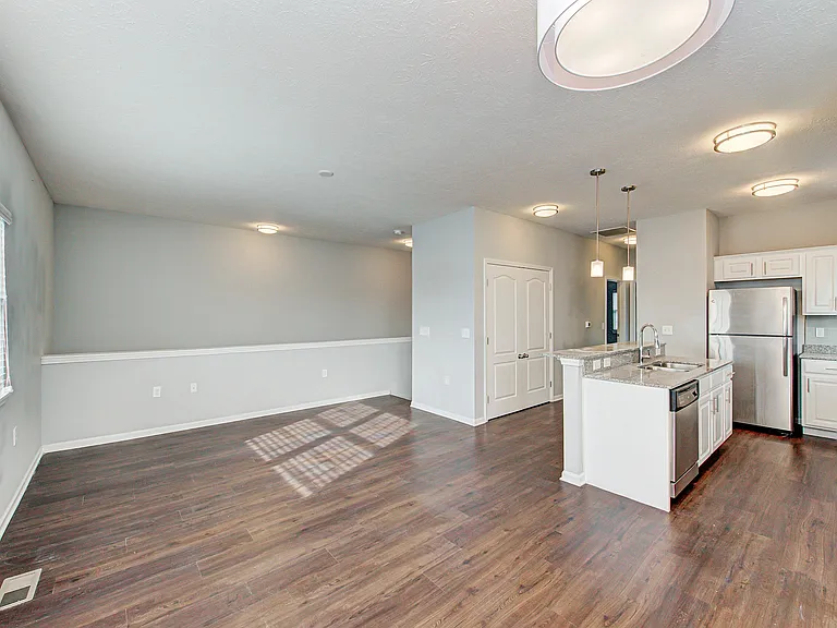 Bright, open-concept townhome living with natural light, wood-style flooring, and stainless steel appliances creates a modern and inviting space to call home.