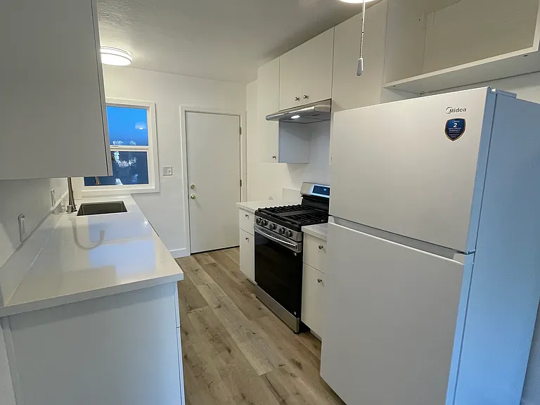 Updated kitchen includes refrigerator stove, quartz countertops and deep stainless steel sink.