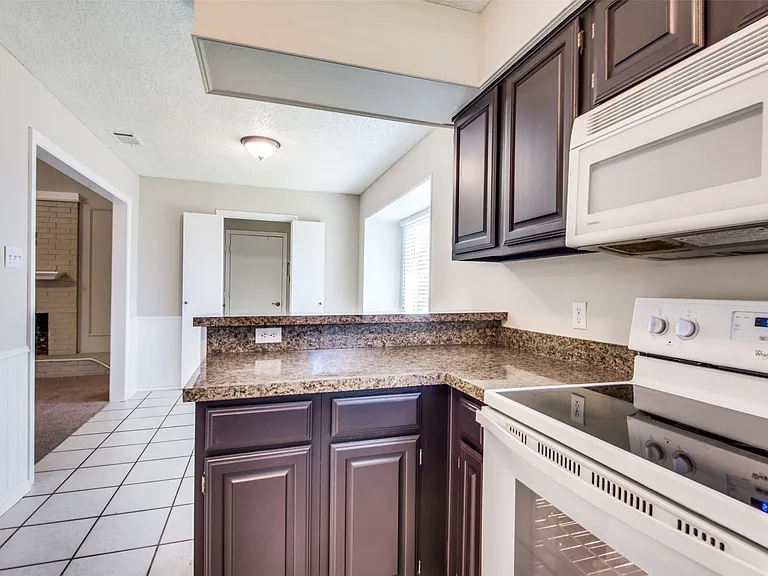 Kitchen featuring dark wood cabinetry, a built-in microwave, and a white electric range