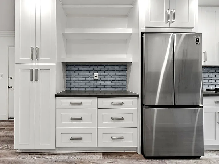 Stainless steel fridge adjacent shelving and storage cabinetry.