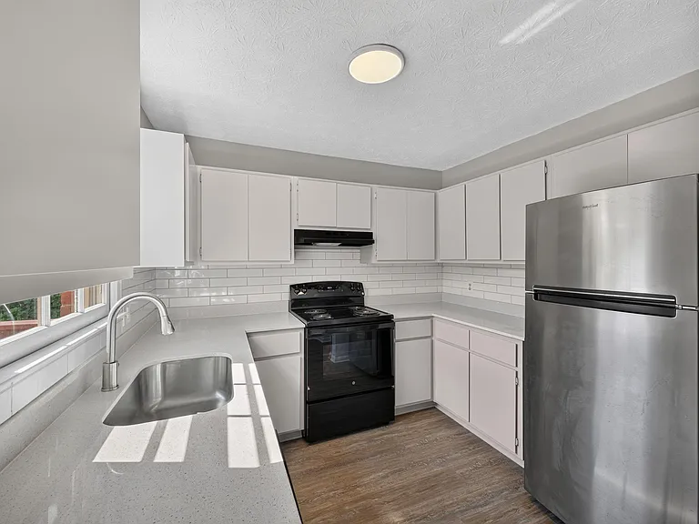 Updated kitchen with ample cabinetry, subway-tile backsplash, stainless refrigerator, and generous counter space by the sink.