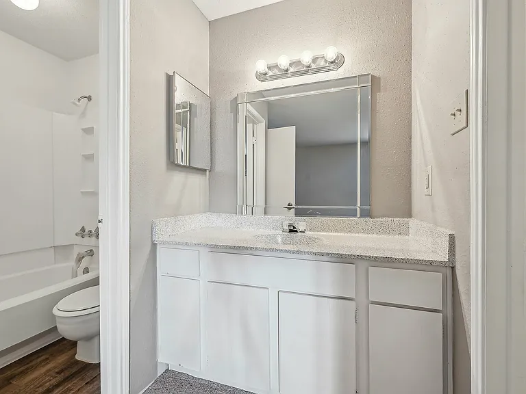 Modern bathroom featuring a sleek vanity, large mirror with ample lighting at Driscoll Place.