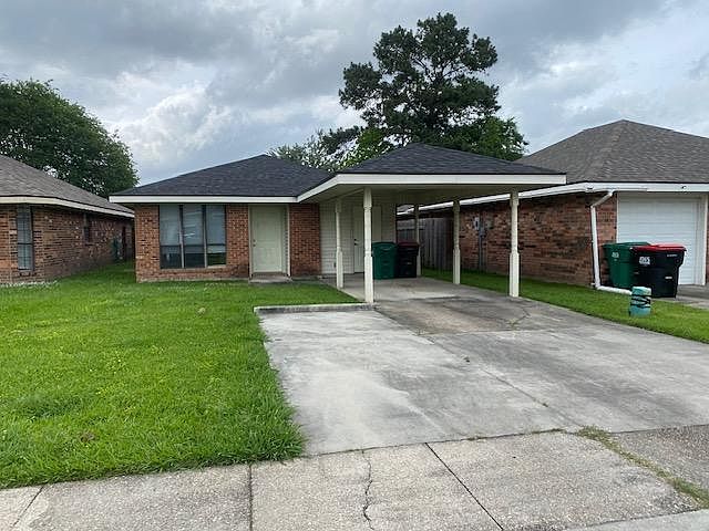 Front view of 108 Doubloon Dr rental . Notice additional cement parking pad for second car. Storage for outside items (yard mower, etc) is provided by closet on house end of carport.