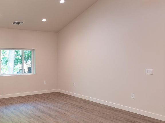 Unit 201: Large open living room with high ceiling and window overlooking trees and K street