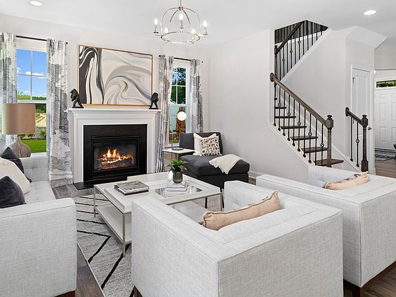 Cozy family room with gas fireplace, 3 large windows, and medium colored wood floors