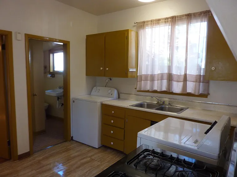 Kitchen with gas stove, washer/dryer, view into bathroom with tub-shower