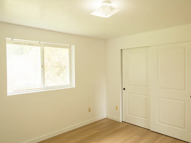 Bright bedroom with large closet, updated flooring, and freshly repainted walls. Clean second-floor space with natural light and peaceful backyard views.