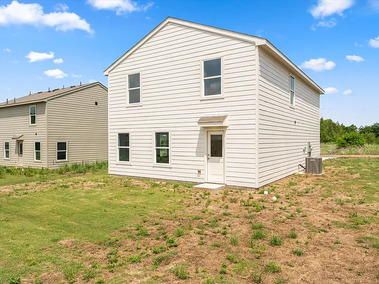 Two-story residence featuring light-colored horizontal siding and multiple windows