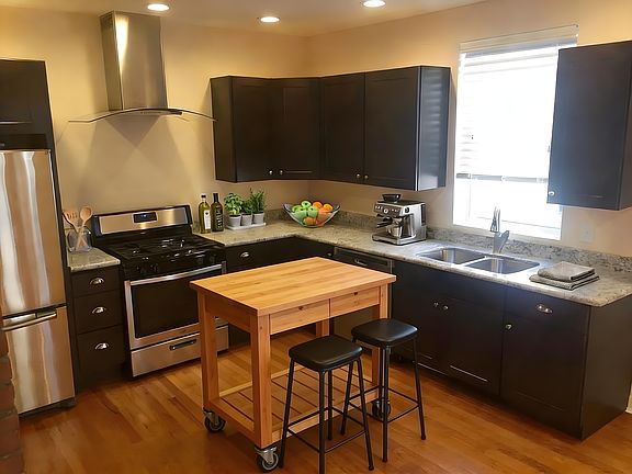 Modern designer kitchen with custom dark cabinetry and granite countertops creates a bold, upscale space built for cooking, hosting, and daily living.
