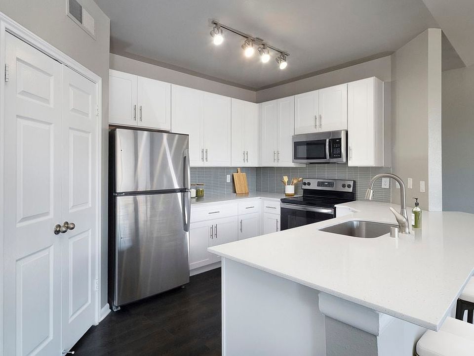 Classic Package II kitchen with stainless steel appliance, white quartz countertop, tile backsplash, white cabinetry, and hard-surface flooring