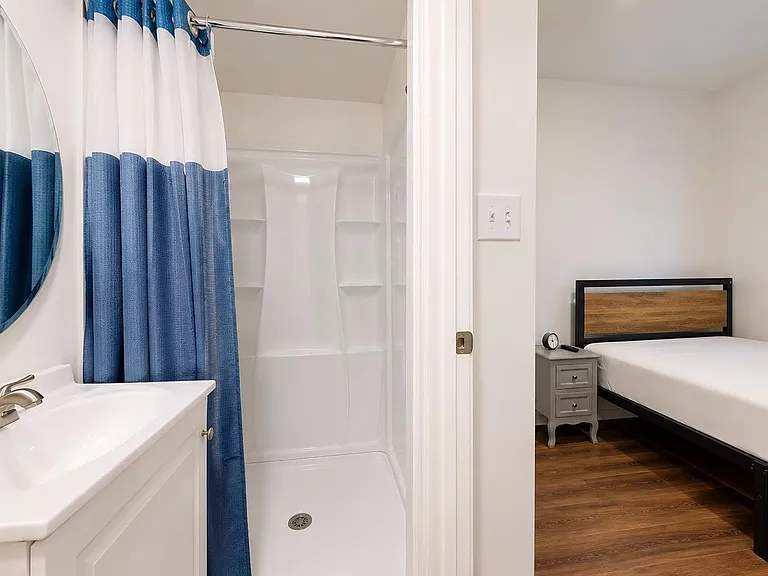 Clean bathroom with tub/shower and vanity sink, plus easy access to an adjacent bedroom with a large window.