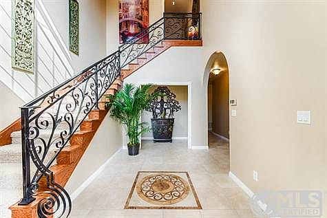 Past the hand-carved dark-oak double doors, a dramatic staircase rises from the porcelain tile floors embedded with artistic tiled medallion. Elegant chandelier can be seen from entry, living room & 2nd dining room.