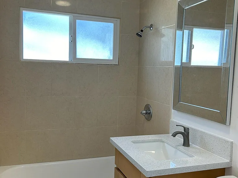 Designer bathroom with tiled shower, glazed tub, brand new designer vanity and mirror