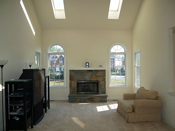 Dramatic two story family room with vaulted ceiling, skylights and fireplace